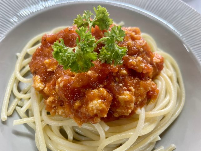 A plate of spaghetti with sauce and parsley